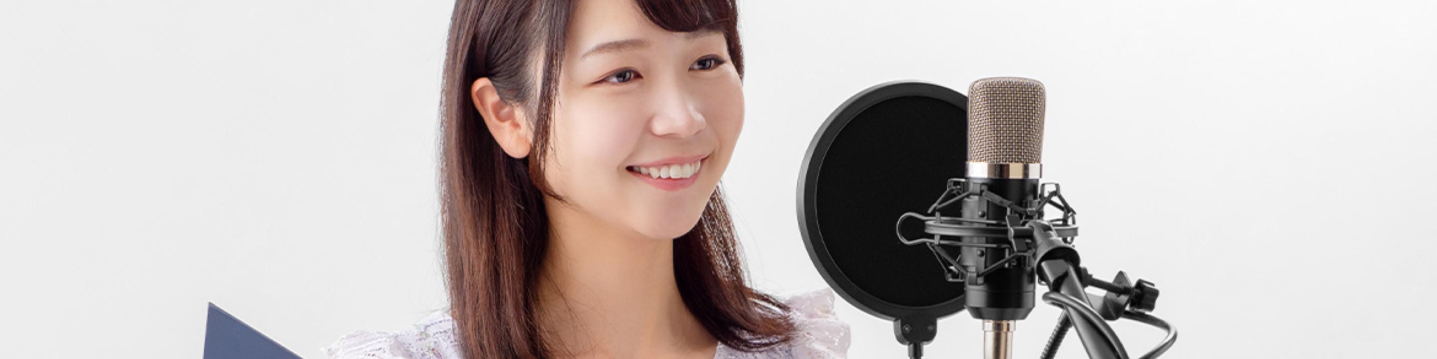 マイクに向かって女性がレコーディングしているイメージ