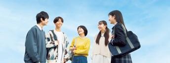 青空の下で立ち話をしている5人の学生たち