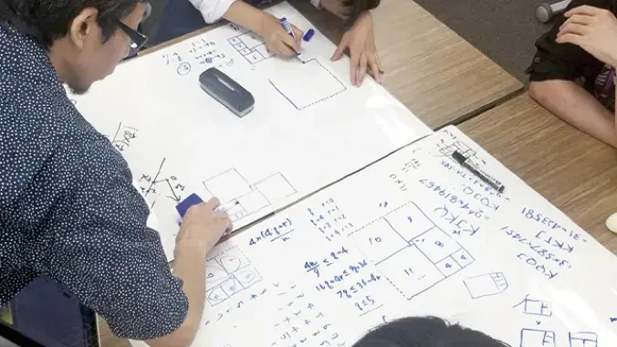 ホワイトボードに数式や図を描く学生たちの様子